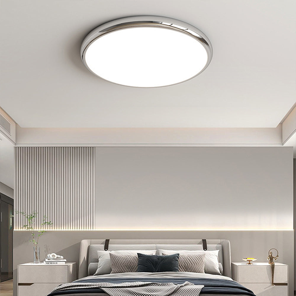 Silver-tone Ozawa flush ceiling light above a bed with grey cushions.