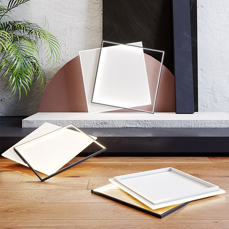 Three Quinn square fixtures staged on a shelf and floor beside a pink semicircle, black board and plant; one shows its rear white tray.