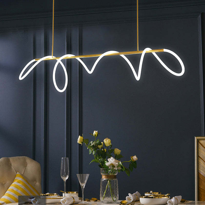 Gold Louise linear light above a dining table with yellow roses, stemmed glasses and gold-rimmed dishes against a blue panelled wall.