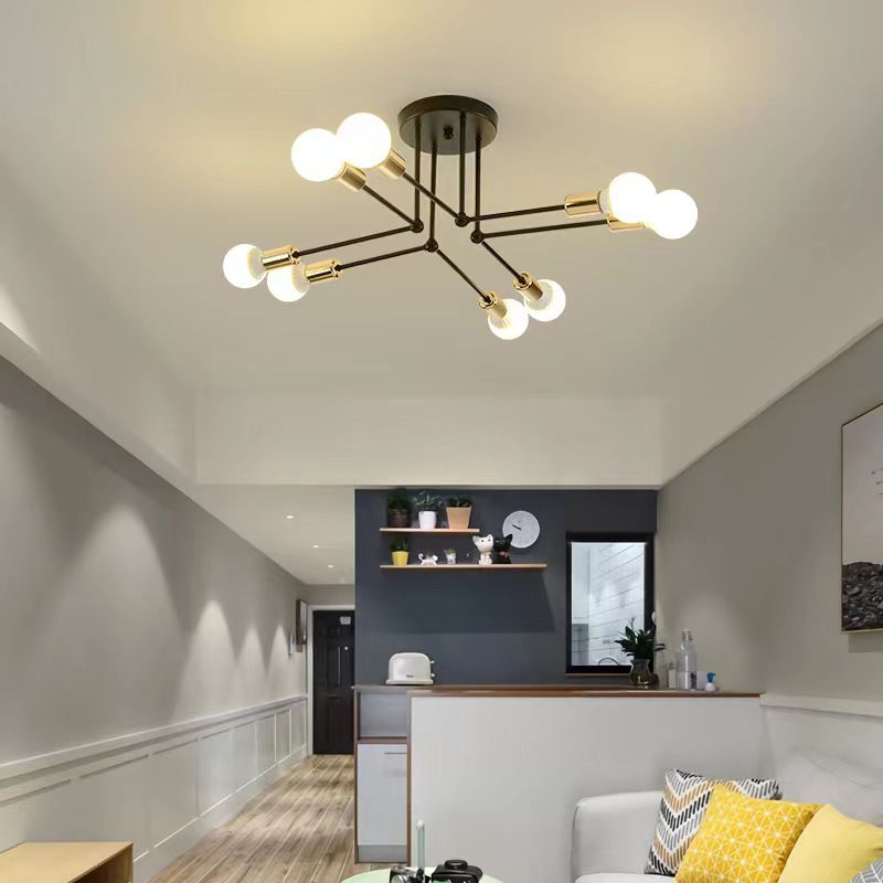 Black-Gold eight-light Valentina near a hallway, dark shelf wall and clock, above a pale sofa with yellow-patterned cushions.