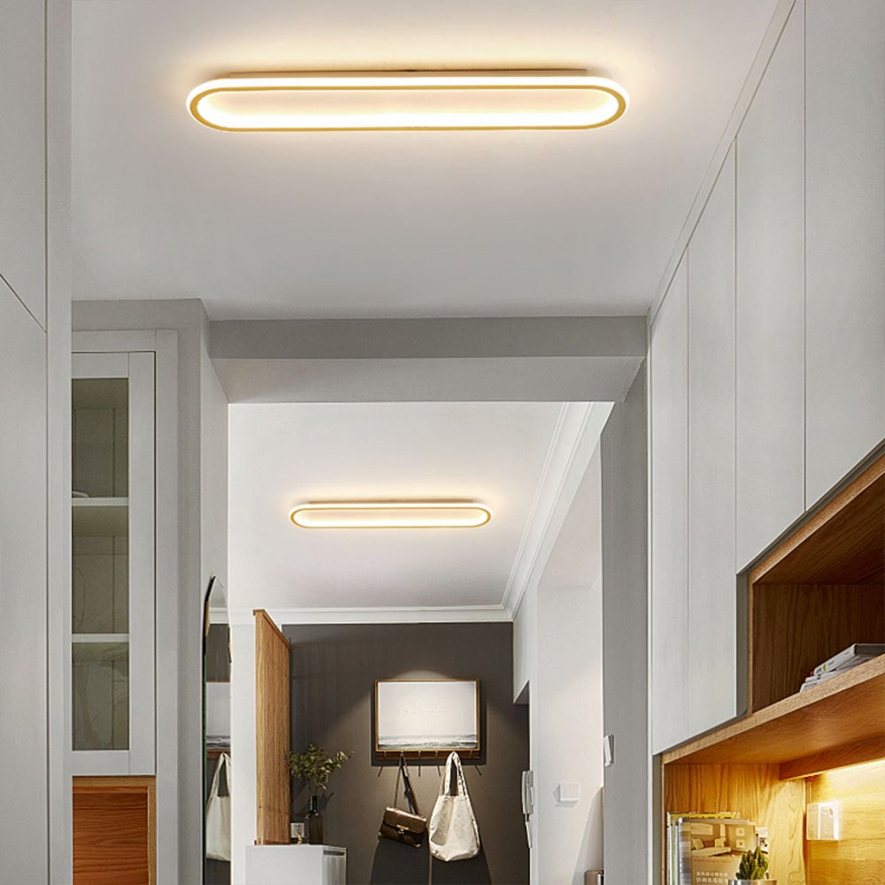 Two Gold Quinn lights in a bright hallway with white cabinets, wood shelves, mirror and hooks holding black and white bags.