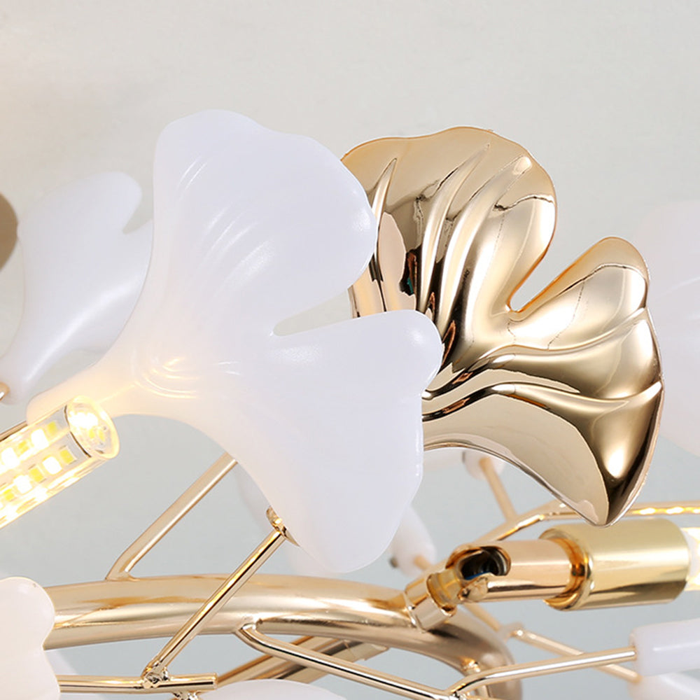 Close-up of Olivia white and reflective gold-tone grooved fan leaves, fine rods and a lit tubular LED beside a gold-tone holder.