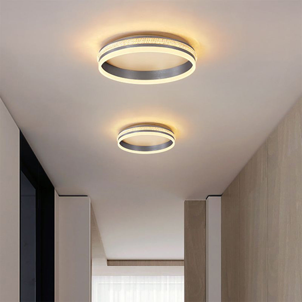 Two lit Quinn ring fixtures along a narrow ceiling passage beside dark window framing and pale wood panels.