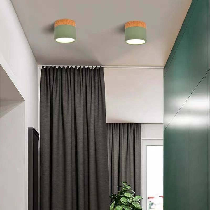 Two green Morandi cylinders above deep-green cupboards, gray curtains, a plant and a wall-mounted television.