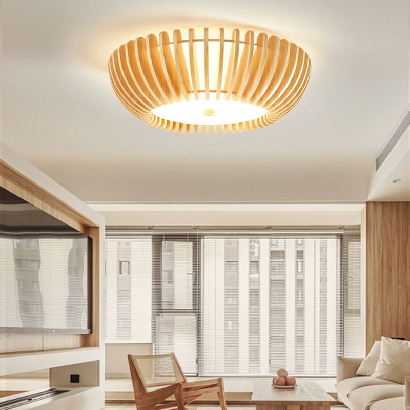Lit Ozawa wood ceiling light in a living room with city-view windows, timber trim, a cane chair, low table and pale sofa.