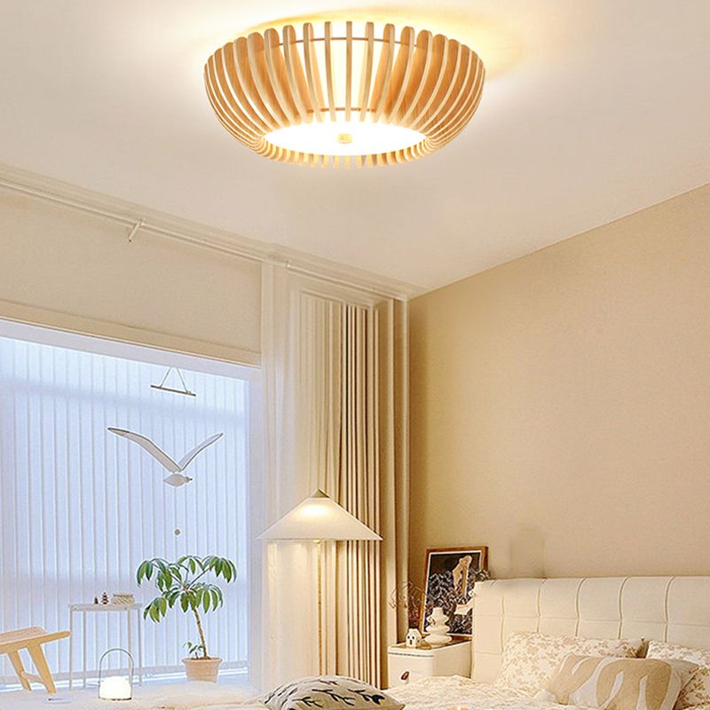 Lit Ozawa ceiling light above a white quilted headboard and pale pillows, beside sheer curtains, a bird mobile and a separate bedside pendant light.