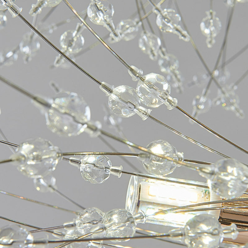 Close-up of Lili’s clear crystal beads and slender branches beside a lit clear bulb and gold-coloured ring fitting.