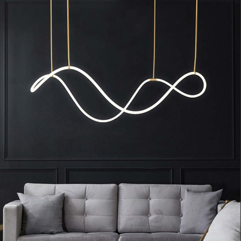 Louise looping white light suspended by two gold-tone vertical elements above a gray sofa and cushions against a dark panelled wall.