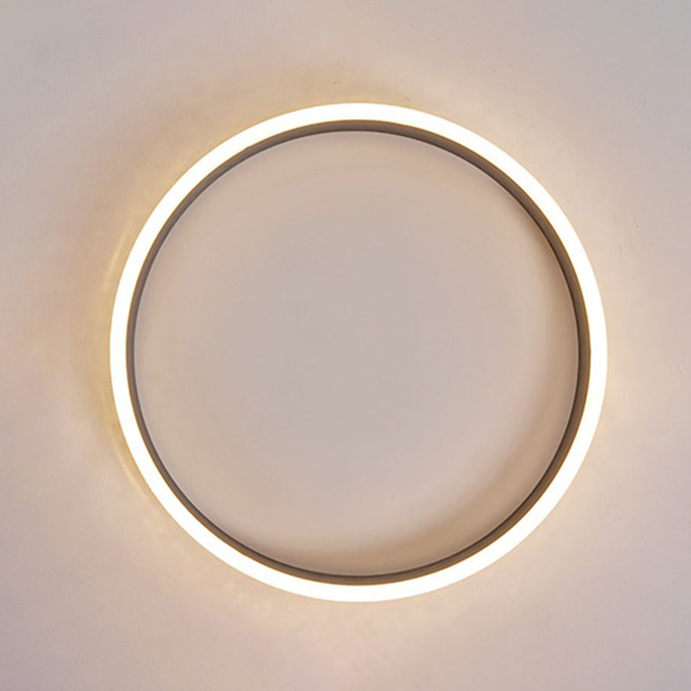View from below of a lit Quinn ring mounted on a pale ceiling, with an open centre, dark inner band and glowing outer edge.