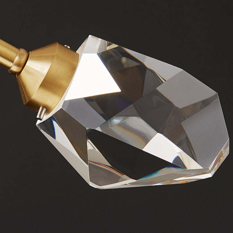 Kristy close-up of a clear irregular faceted shade, gold-tone cap, projecting screw and metal arm.