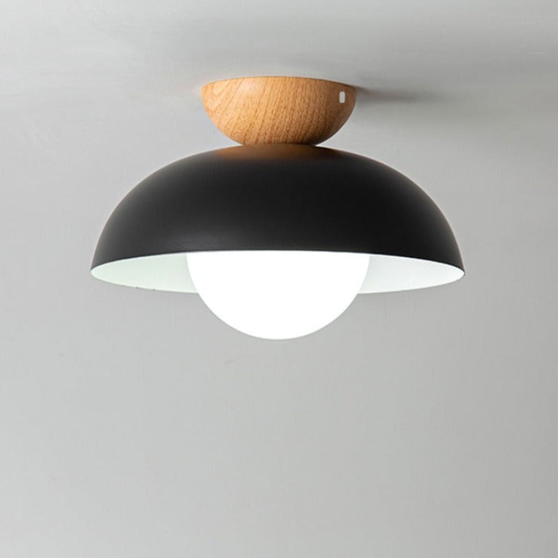 Close view of black Ozawa ceiling light with wood crown against the ceiling and a glowing white globe below