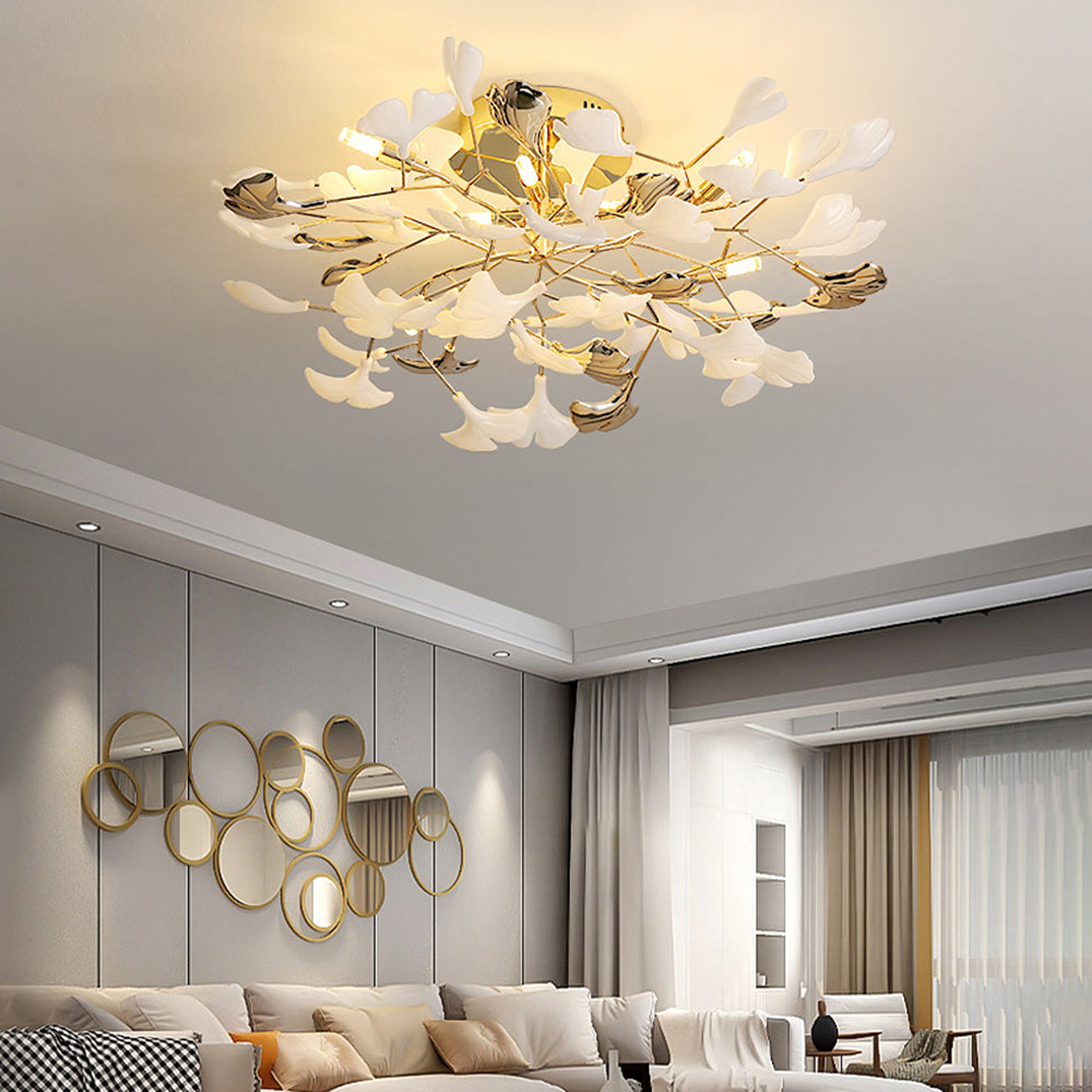 Olivia white and gold-tone leaf light above a pale sofa with checked cushions and grouped gold-framed round mirrors.
