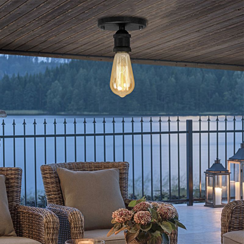 Black Alessio canopy and short holder beneath a wood ceiling, with an exposed filament-style bulb above wicker seating and a lake view.