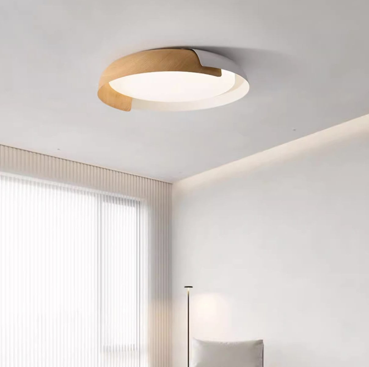 Warm-lit wood-tone and light Quinn ceiling frame above a pale seating corner beside sheer curtains and a slim floor lamp.