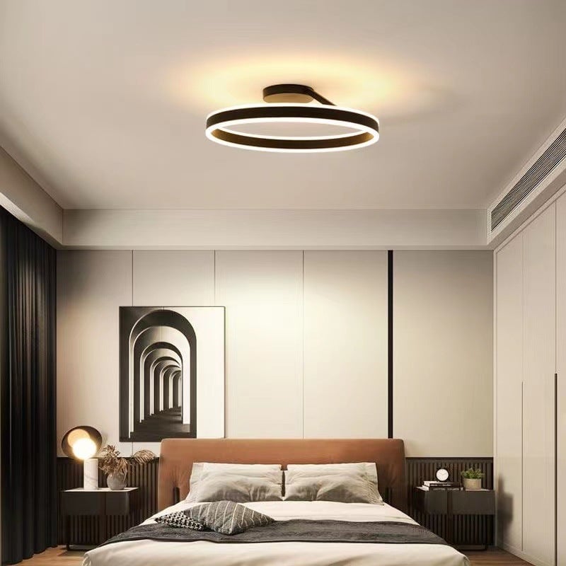 Black upper-and-lower-lit ring above a bedroom with brown headboard and framed arch art