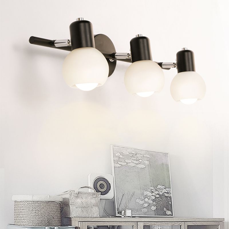 Black Valentina three-head wall light above a cabinet with baskets and artwork