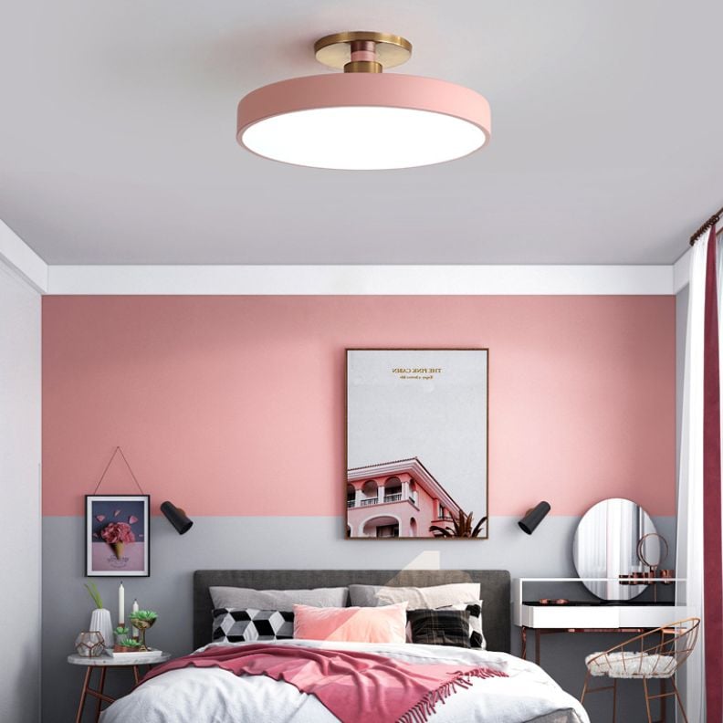 Pink round ceiling fixture above a pink and gray bedroom with a vanity mirror