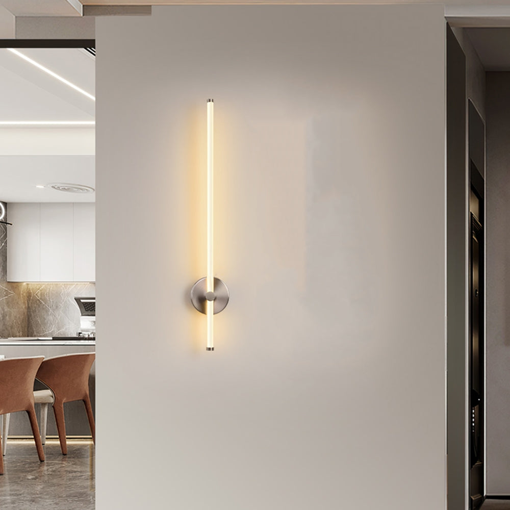 Silver-tone Edge round-backplate wall light with a glowing vertical rod beside a kitchen and dining opening