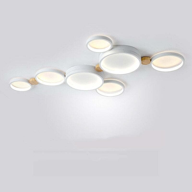 White seven-head ceiling light with linked discs and a small branch below the central panel