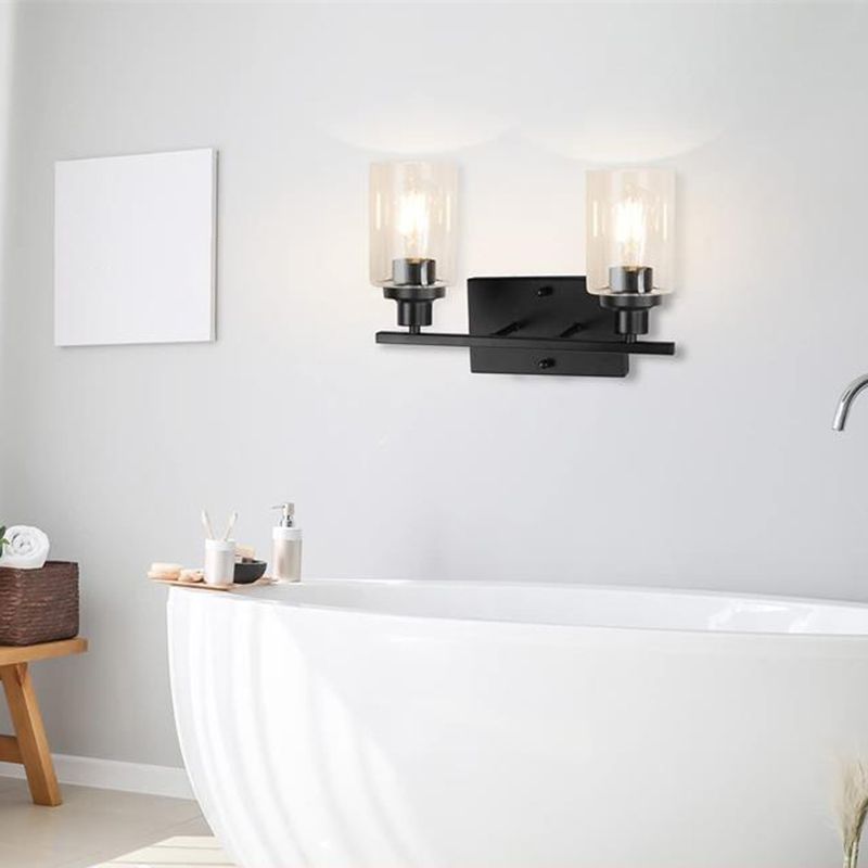 Black Alessio two-light wall bar with upward clear glass cylinders above a bathtub