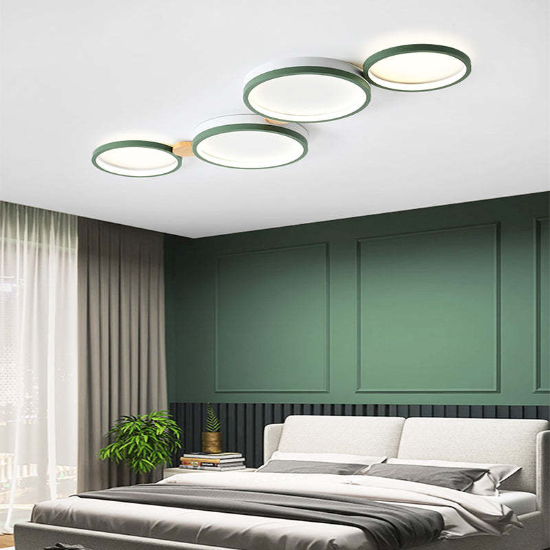 Green four-head disc ceiling light above a bed against a green paneled wall