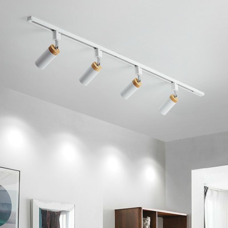 White four-head ceiling rail light with angled tubular spots above framed art and a shelf