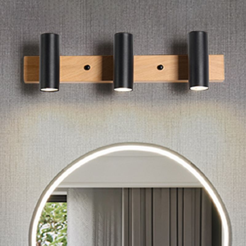 Three black heads above a backlit round mirror on a grey textured wall