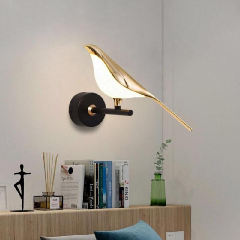 Gold bird light above books on a low cabinet
