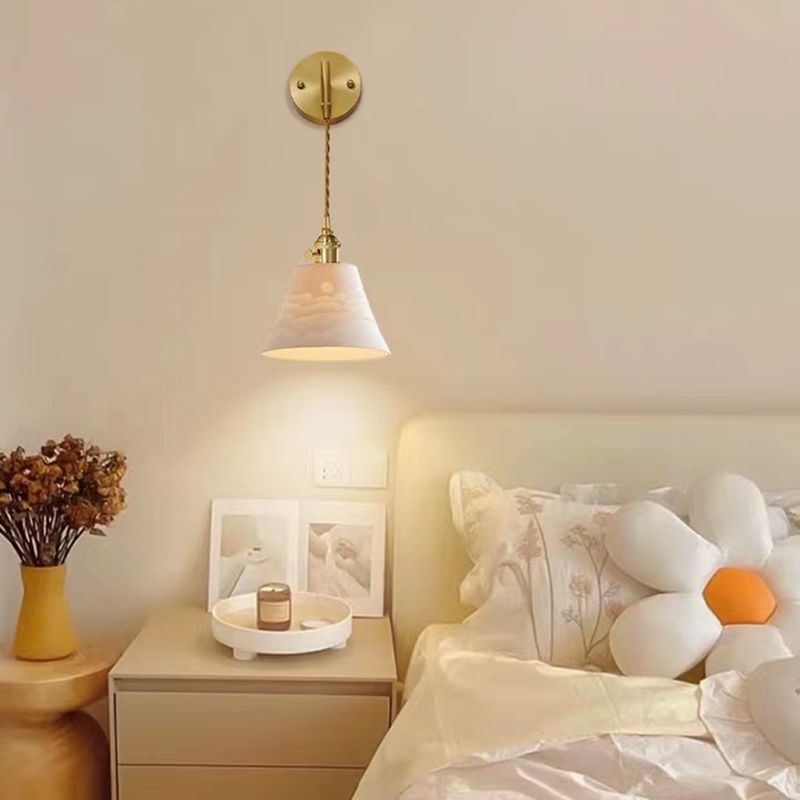 Lottie white relief cone wall light above a bedside table beside cushions and flowers