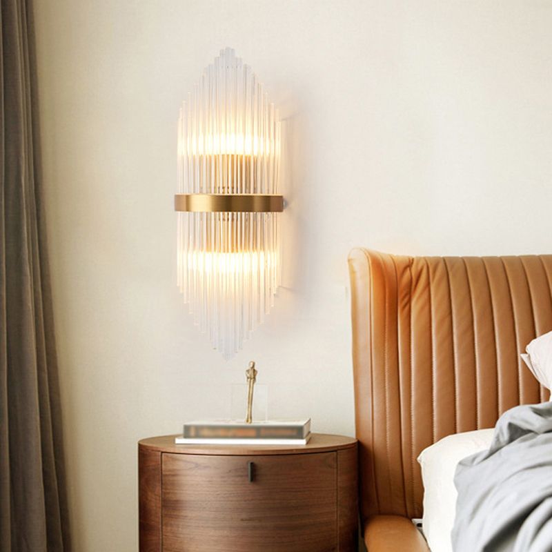 Kristy B clear-rod wall light beside a tan headboard and round wood nightstand