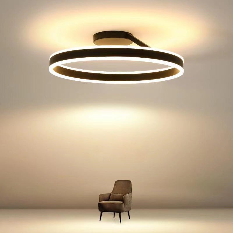 Black ring with illuminated upper and lower rims and ceiling glow above a brown chair