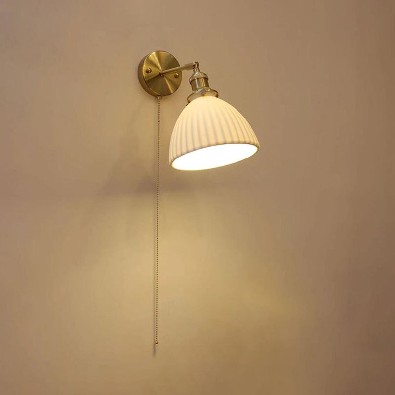 Lottie illuminated white domed pleated shade on a pale wall with a long hanging bead chain
