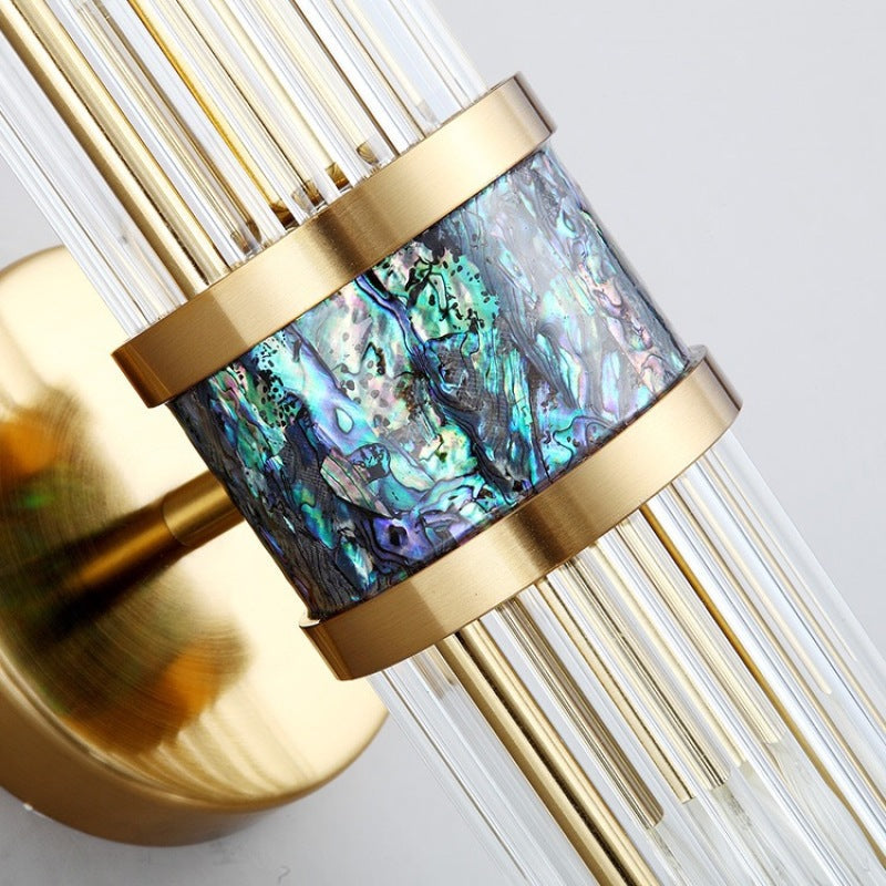 Close-up of an iridescent-looking blue-green patterned band between gold-tone rings and clear rods