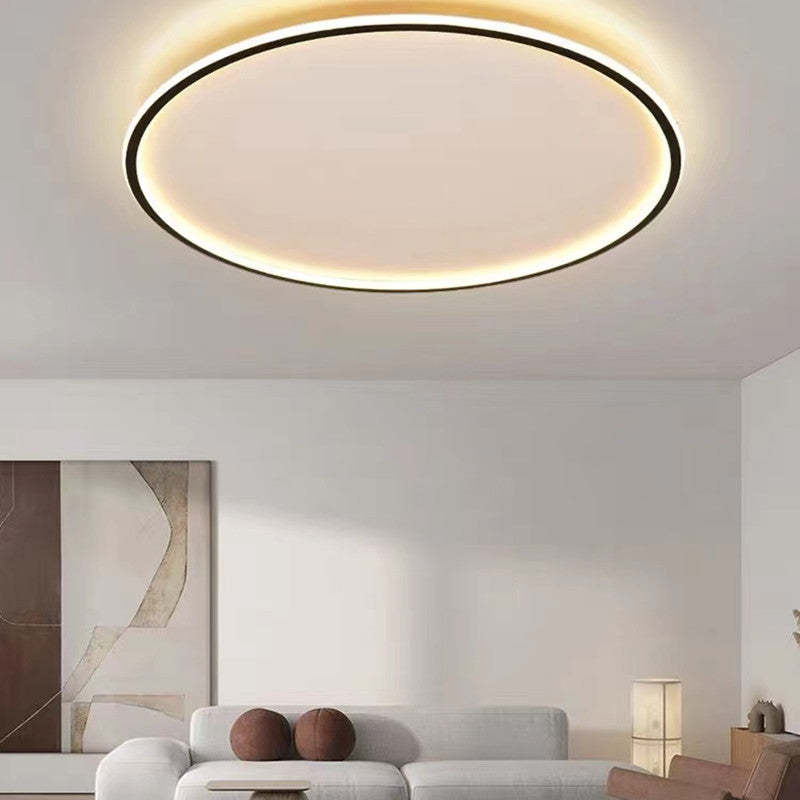 Black-edged LED ceiling ring above a White sofa with Brown round cushions, an abstract picture and coffee table