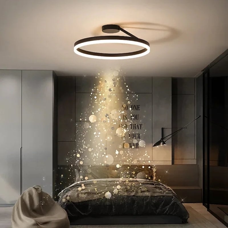 Black ring ceiling fixture above a bedroom with wall lettering and a separate wall light