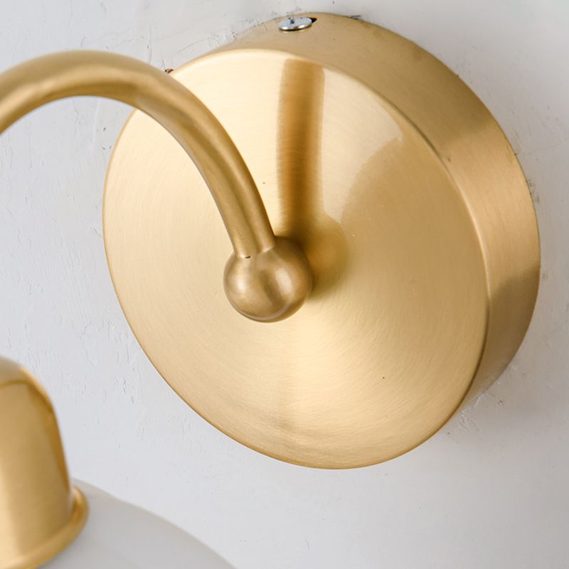 Detail of the circular brushed gold-tone wall plate, curved arm connection and top fixing screw