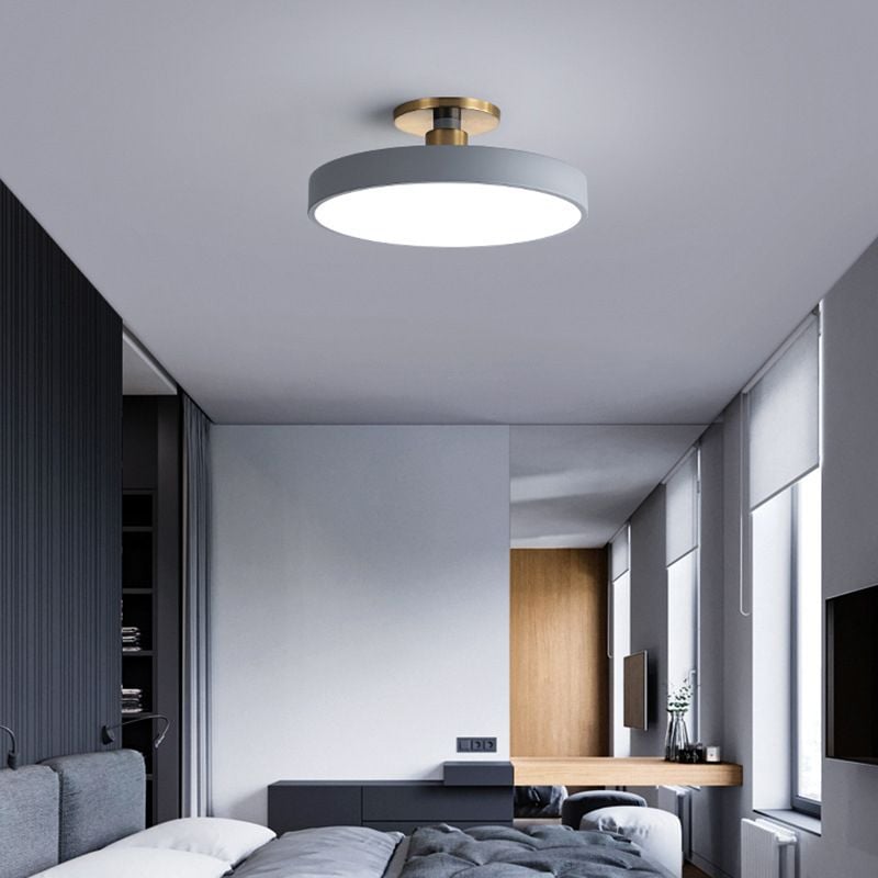 Gray round ceiling fixture above a bedroom near windows and a dark headboard