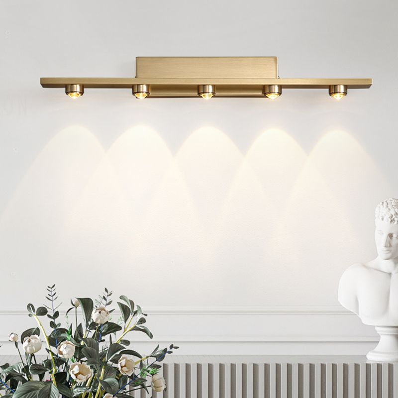 Leigh five-light gold-tone wall lamp above plants and a white bust on a pale paneled wall