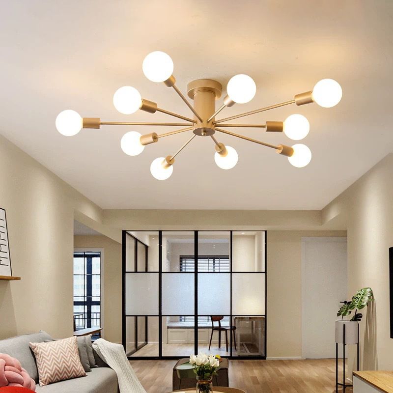 Gold ten-light ceiling fixture above a living room with sofa, cushions, plants and glass partition