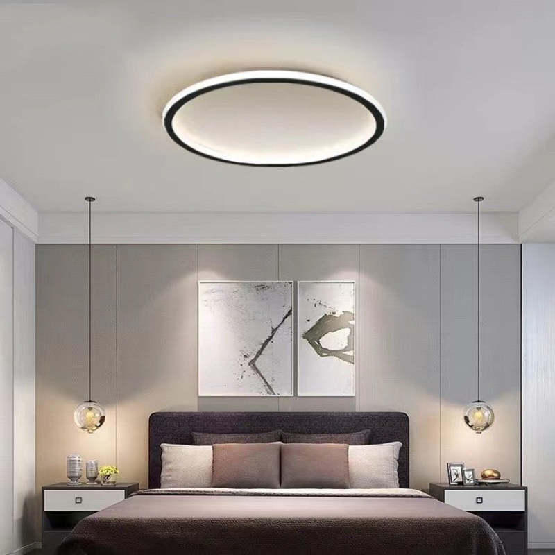 Black LED ceiling ring above a bed with pillows, framed artwork and two hanging glass globe pendants