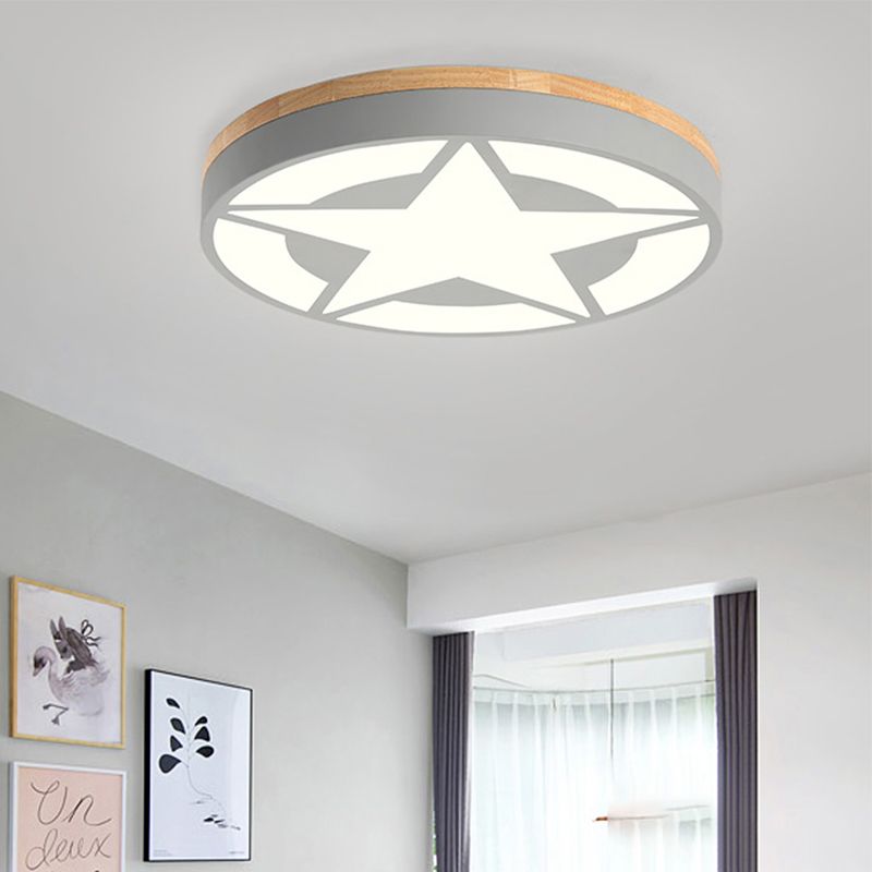 Grey round star ceiling light near framed artwork and a window, with illuminated panels and wood-tone trim