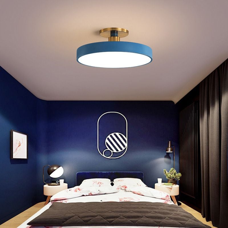 Blue round ceiling fixture above a blue bedroom with oval outline and striped circular wall art