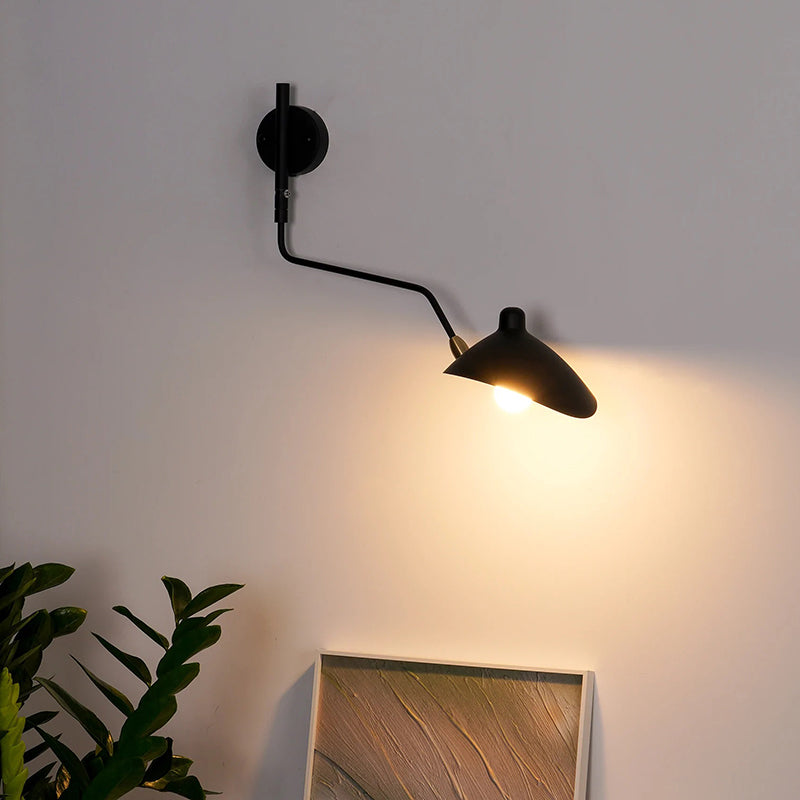 Black bent-arm wall light illuminating artwork below