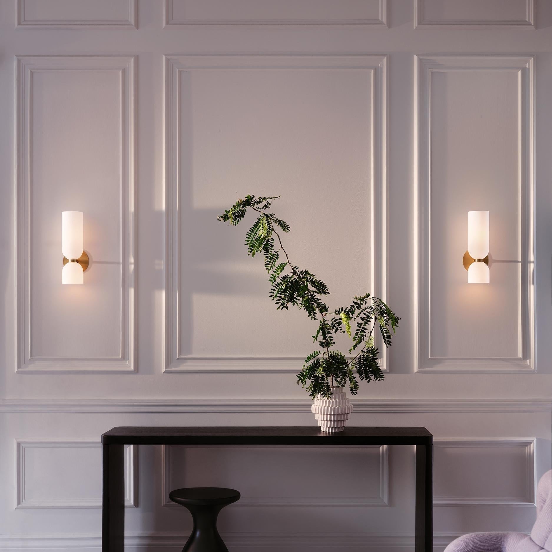 White wall lamps around decorative paneling and a console