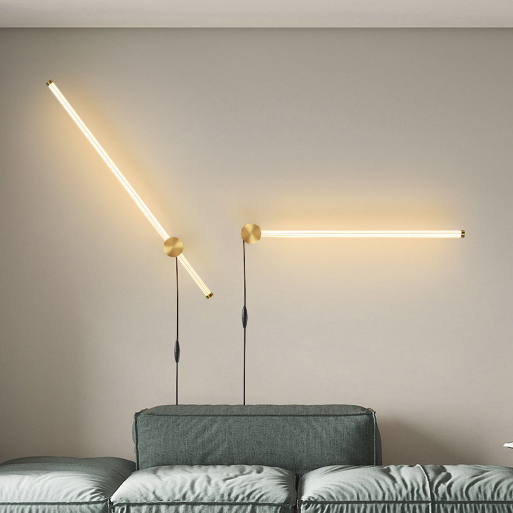 Two gold-tone Edge rod wall lights above a sofa, shown diagonally and horizontally with hanging cords