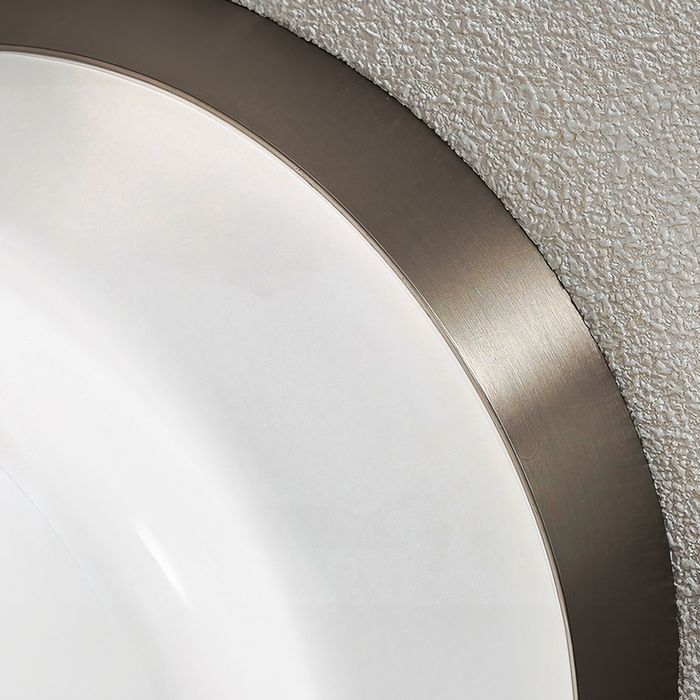 Extreme close-up of a pale circular diffuser beside a brushed metal rim on a textured surface