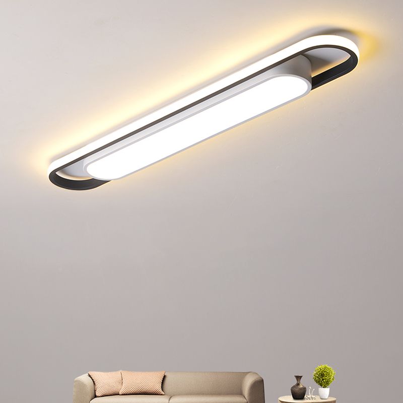 Angled lit linear ceiling fixture above a beige sofa, small table and green plant