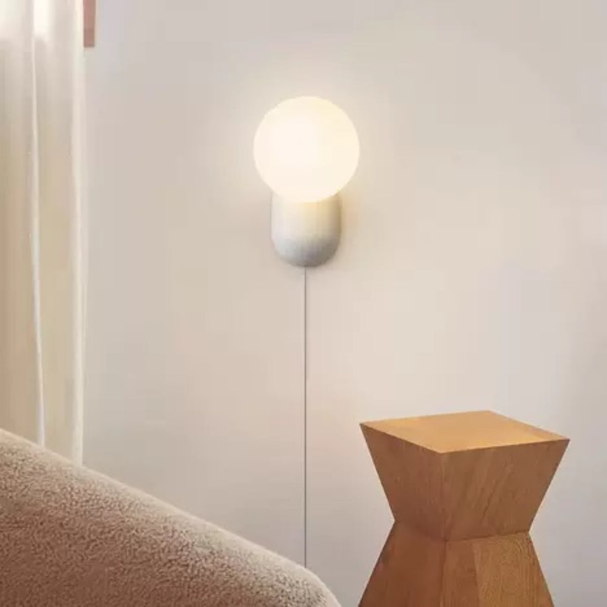 White Hailie glass globe wall light beside a sofa