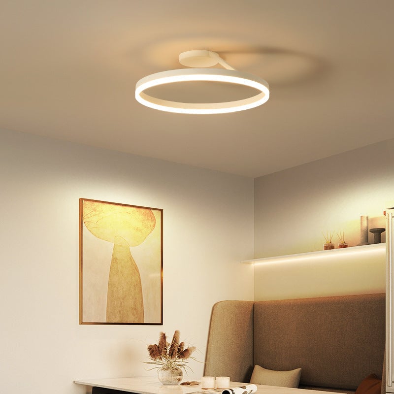 White illuminated ring ceiling fixture above a booth, cups, framed art and a shelf