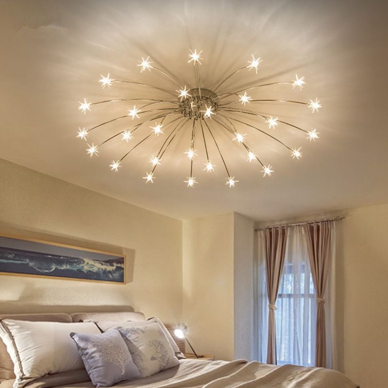 Chrome-tone starburst ceiling light with radial shadows above pale bed beside framed landscape and curtained window